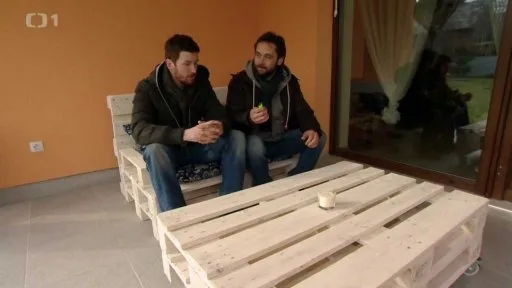 Dva muži sedí na lavičce z palet vedle stolku vyrobeného ze dřevěných palet.