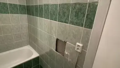 Koupelna s umakartem po renovaci – viditelná škoda na dlažbě.