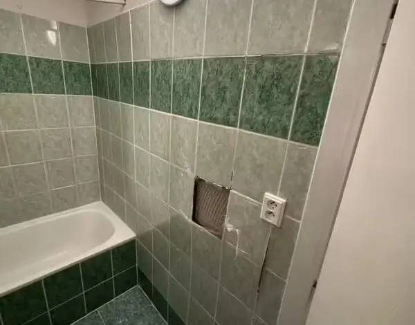 Koupelna s umakartem po renovaci – viditelná škoda na dlažbě.