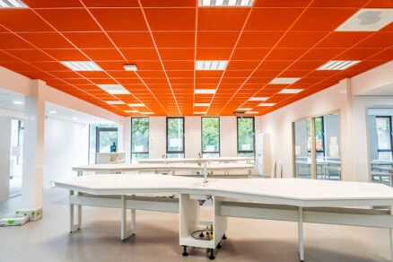 Oranžové akustické podhledy v interiéru školní učebny nebo laboratoře.