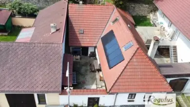 Dům s fotovoltaickými panely na střeše a tepelným čerpadlem.