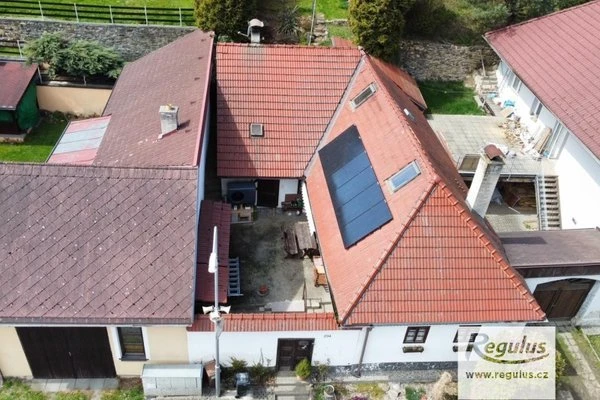 Dům s fotovoltaickými panely na střeše a tepelným čerpadlem.