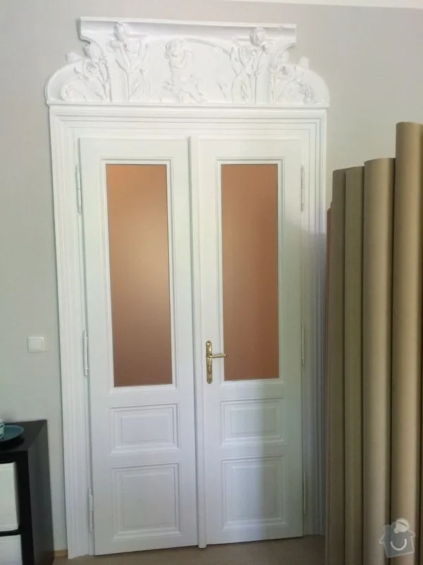 Bílé dvoudveřové dveře s výplněmi a dekorativním rámem po renovaci.
