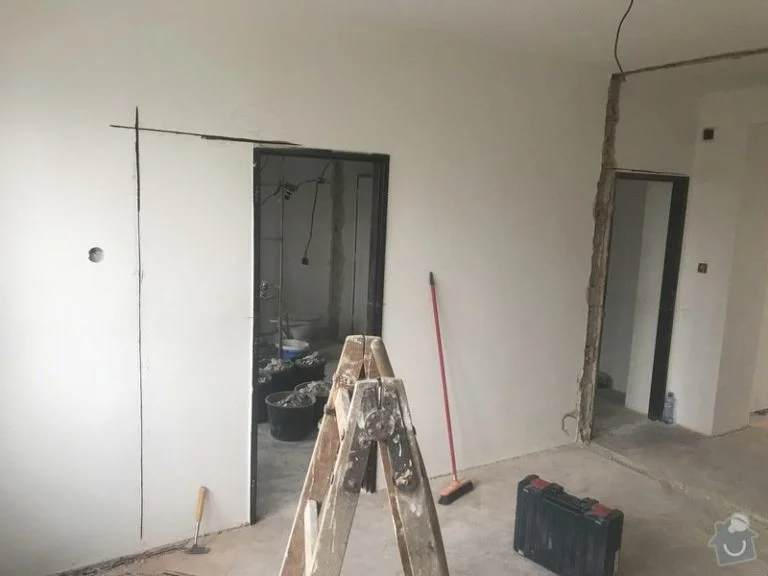 Interiér bytu v rekonstrukci s viditelnými nástroji a nehotovými stěnami.