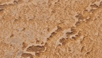 Detail světle hnědé fasády s texturou omítky nebo kamene.