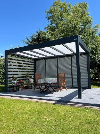 Moderní zasklená pergola s roletami na zahradě.