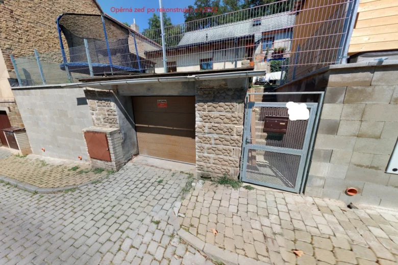Opěrná zeď z kamene s kovovým plotem na ulici.